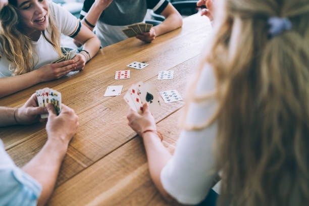 Personer spelar kort tillsammans runt ett träbord